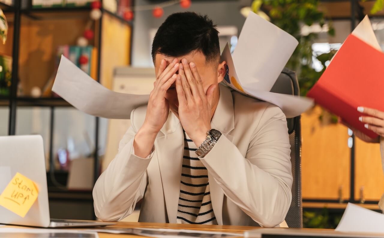 A man covering his face with his hands, looking distressed. 