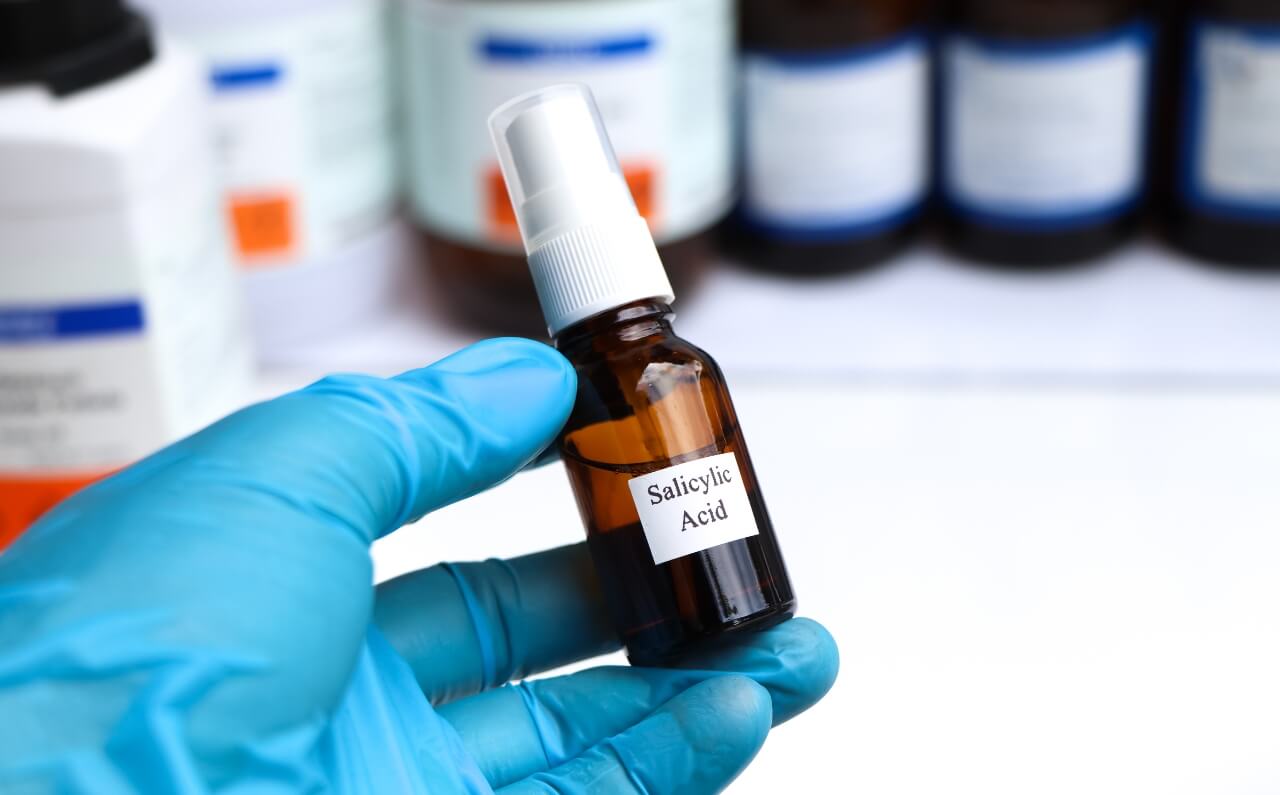 An aesthetician holding a bottle of acne treatment.