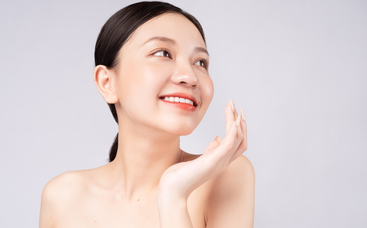 A woman smiling, showing clear skin.