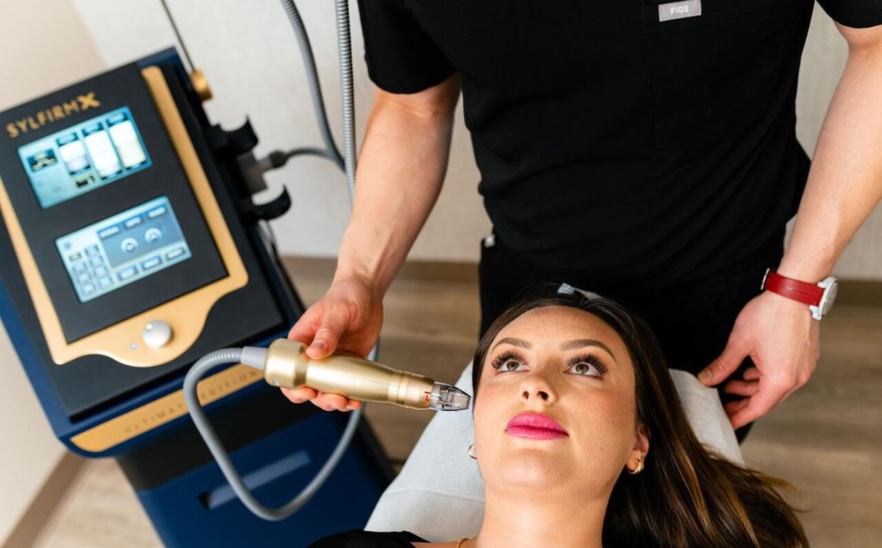 A aesthetician performing a Sylfirm X treatment on patient's skin.