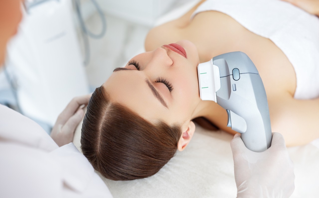 Woman receiving HIFU treatment on face to lift and tighten sagging skin.