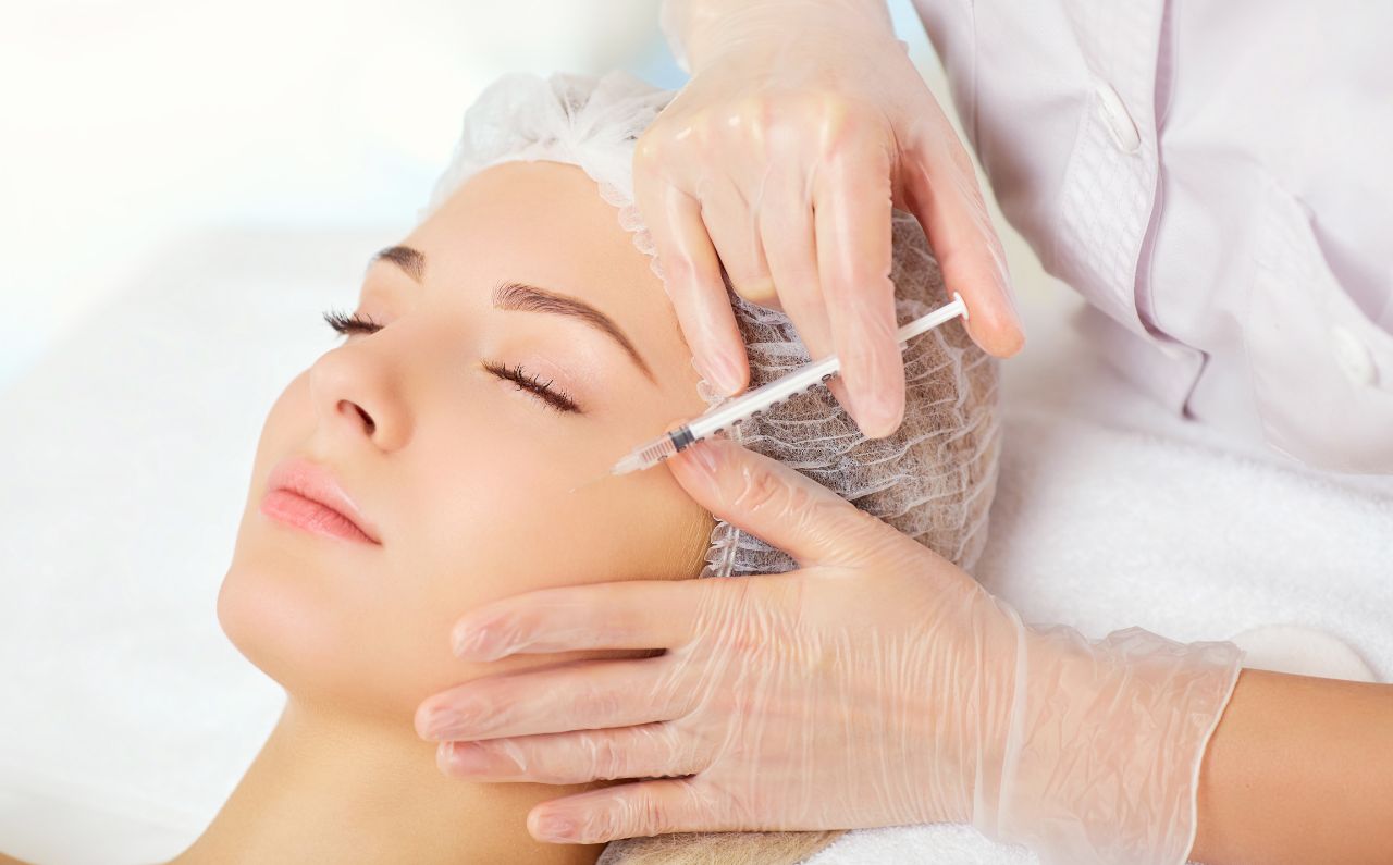 Aesthetician performing microinjections of skin booster on a woman’s face.