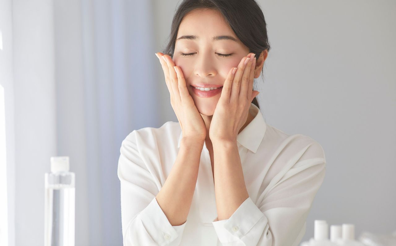 Smiling woman patting her face after JuveLook treatment, enjoying benefits beyond wrinkle reduction.