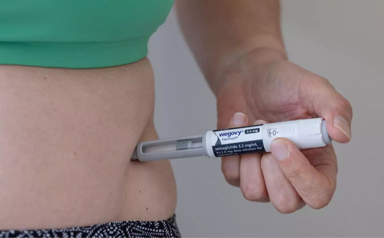 Person self-injecting Wegovy® in the abdomen for weight loss treatment