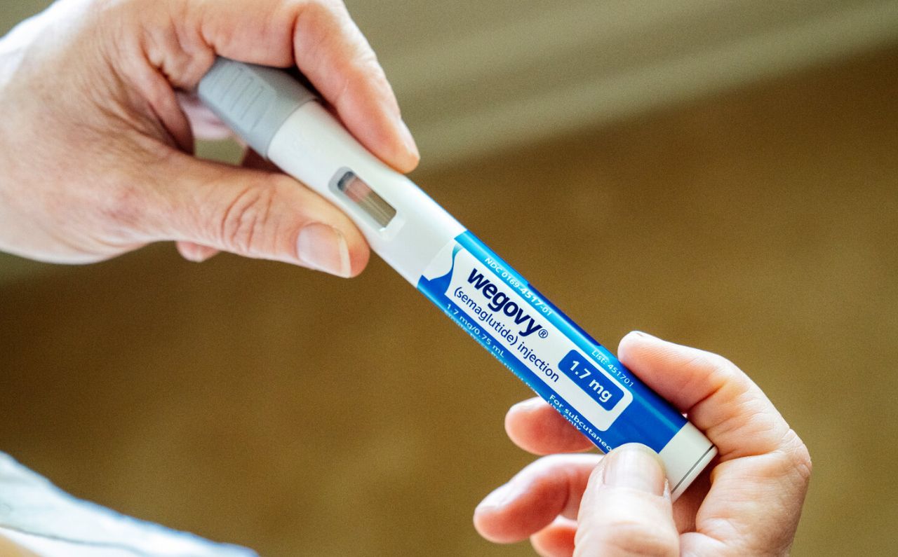 A person holding a Wegovy® injection pen for weight loss treatment.