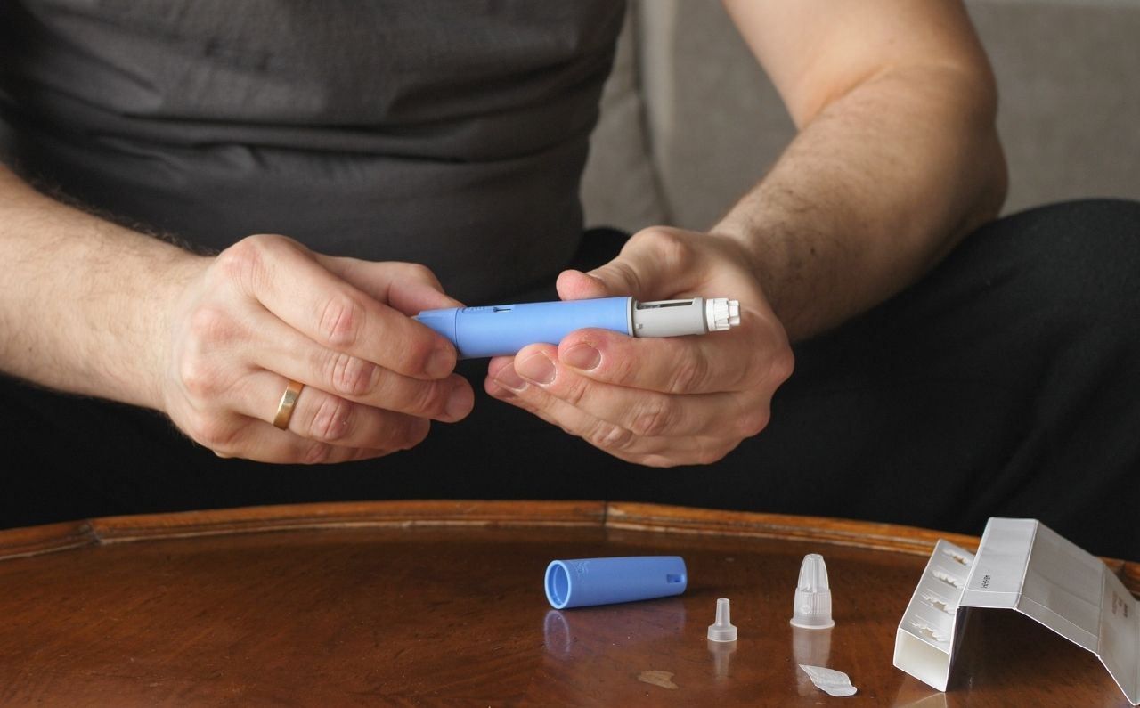 Man holding a weight loss injection device, representing Mounjaro® and other injectable treatments for appetite control and weight management.