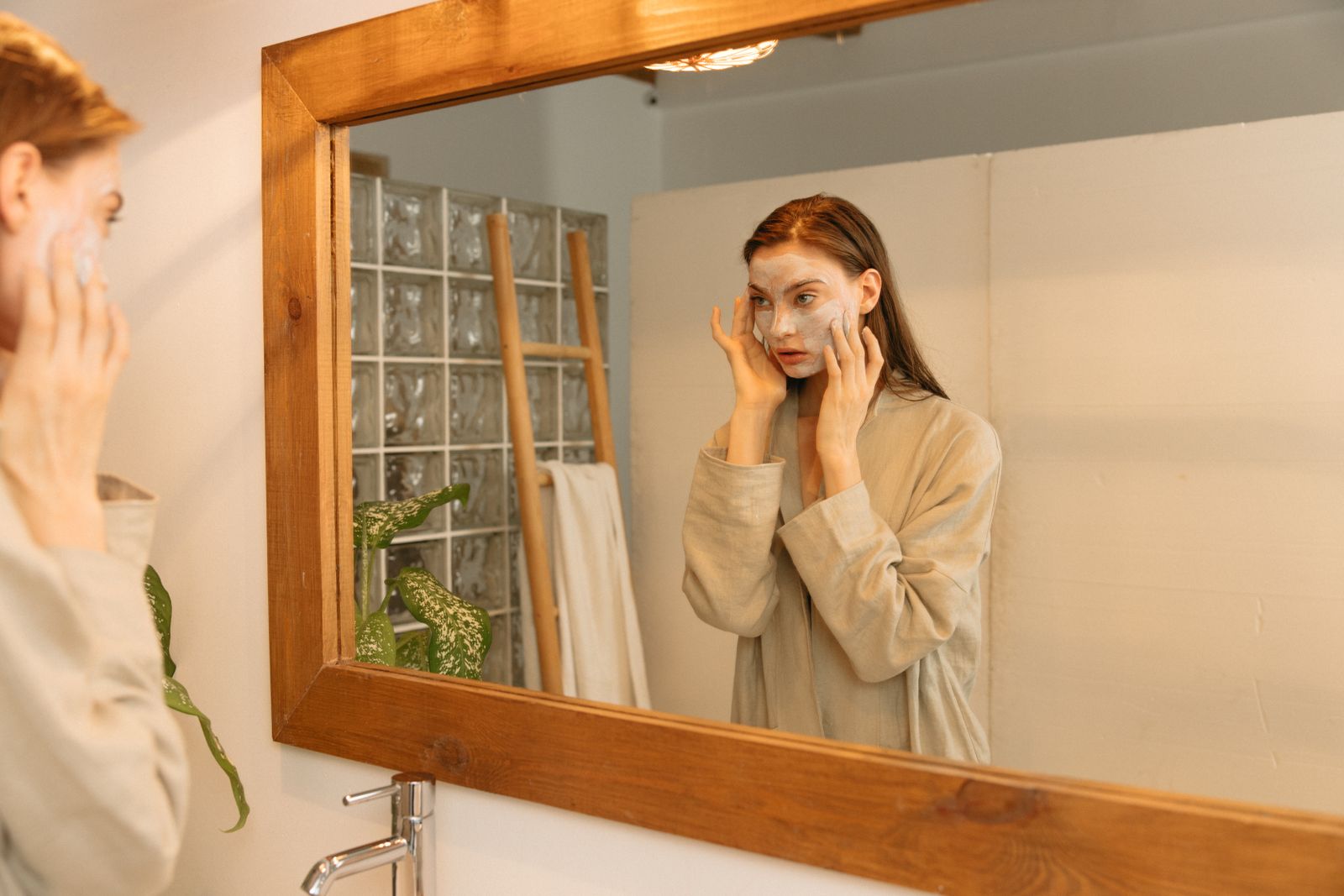 Woman observing her skin in a mirror during a skincare routine