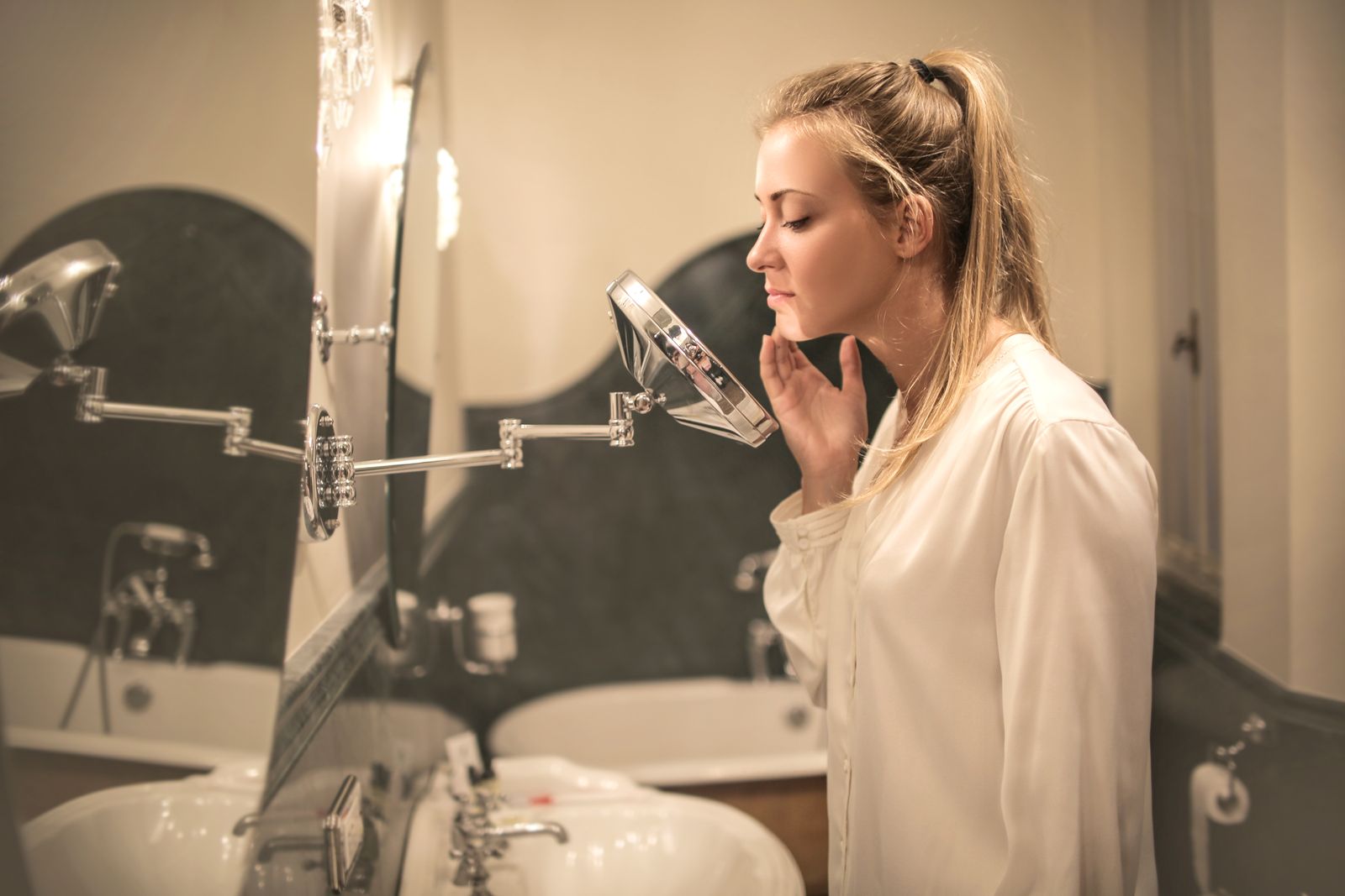 Woman closely examining facial skin and contours in a mirror
