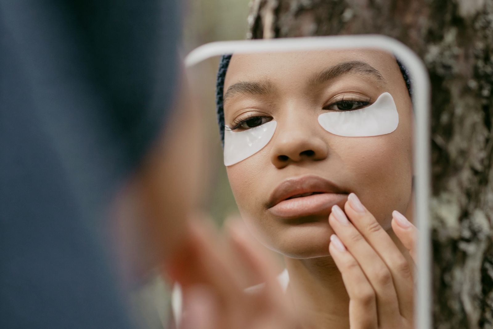 Woman looking at the eye and cheek area while using a mirror
