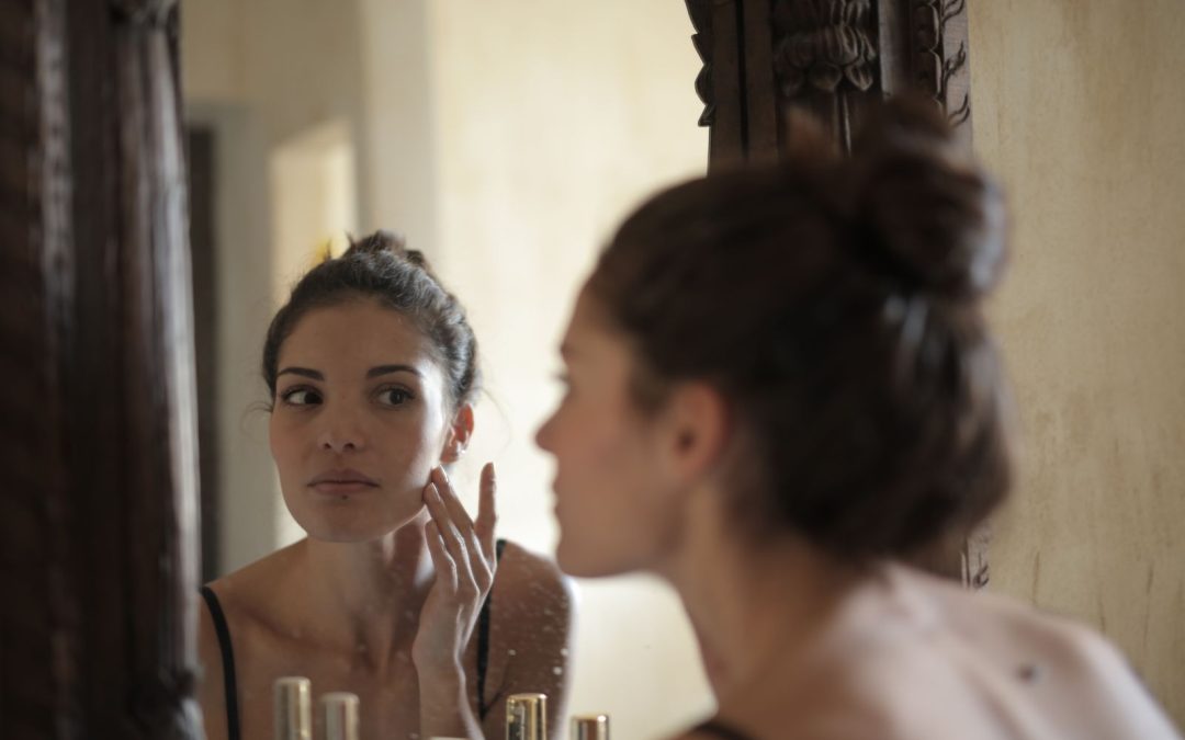 Woman examining the cheek and lower-face area in a mirror