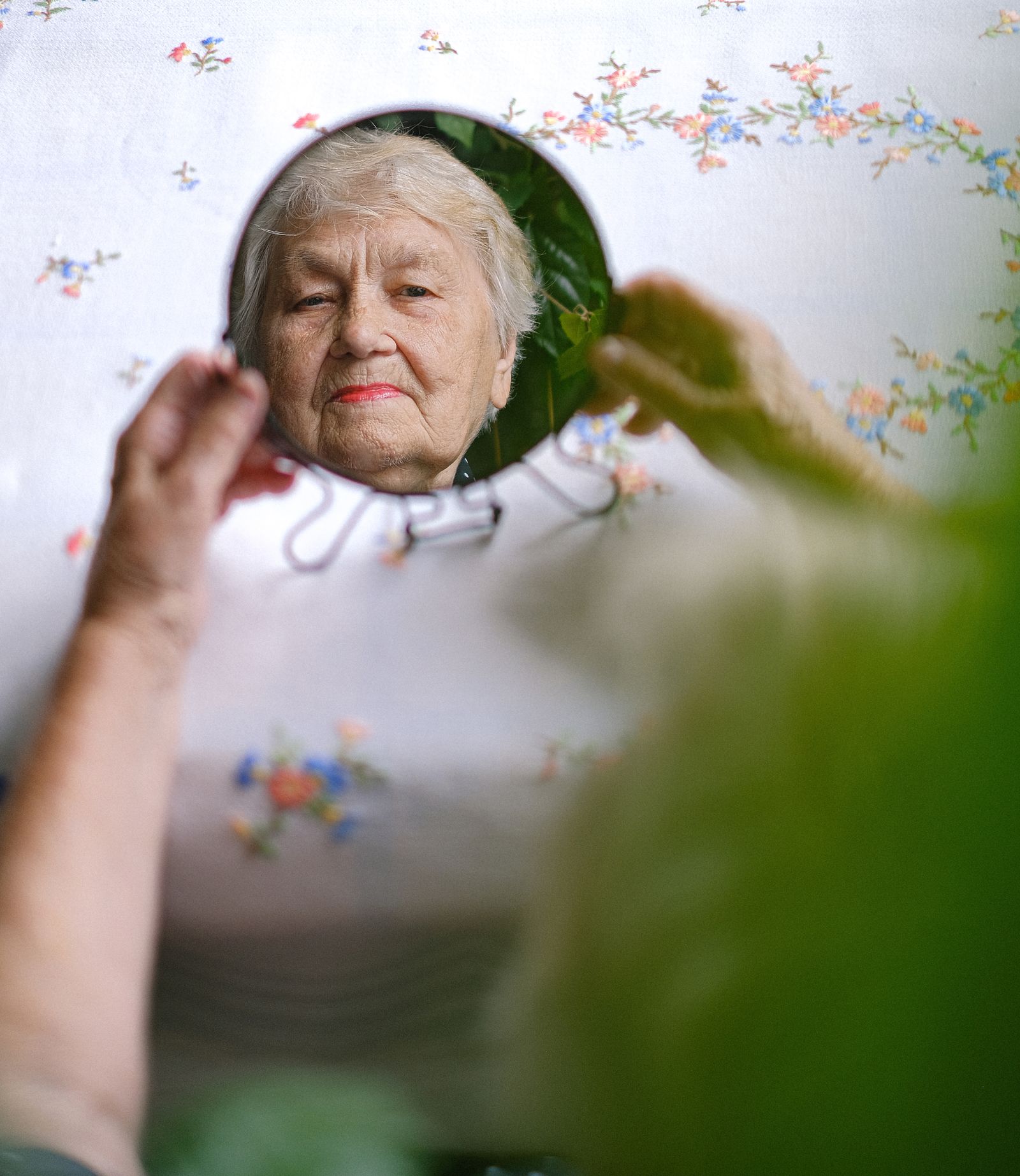 Mature woman looking at her reflection in a handheld mirror