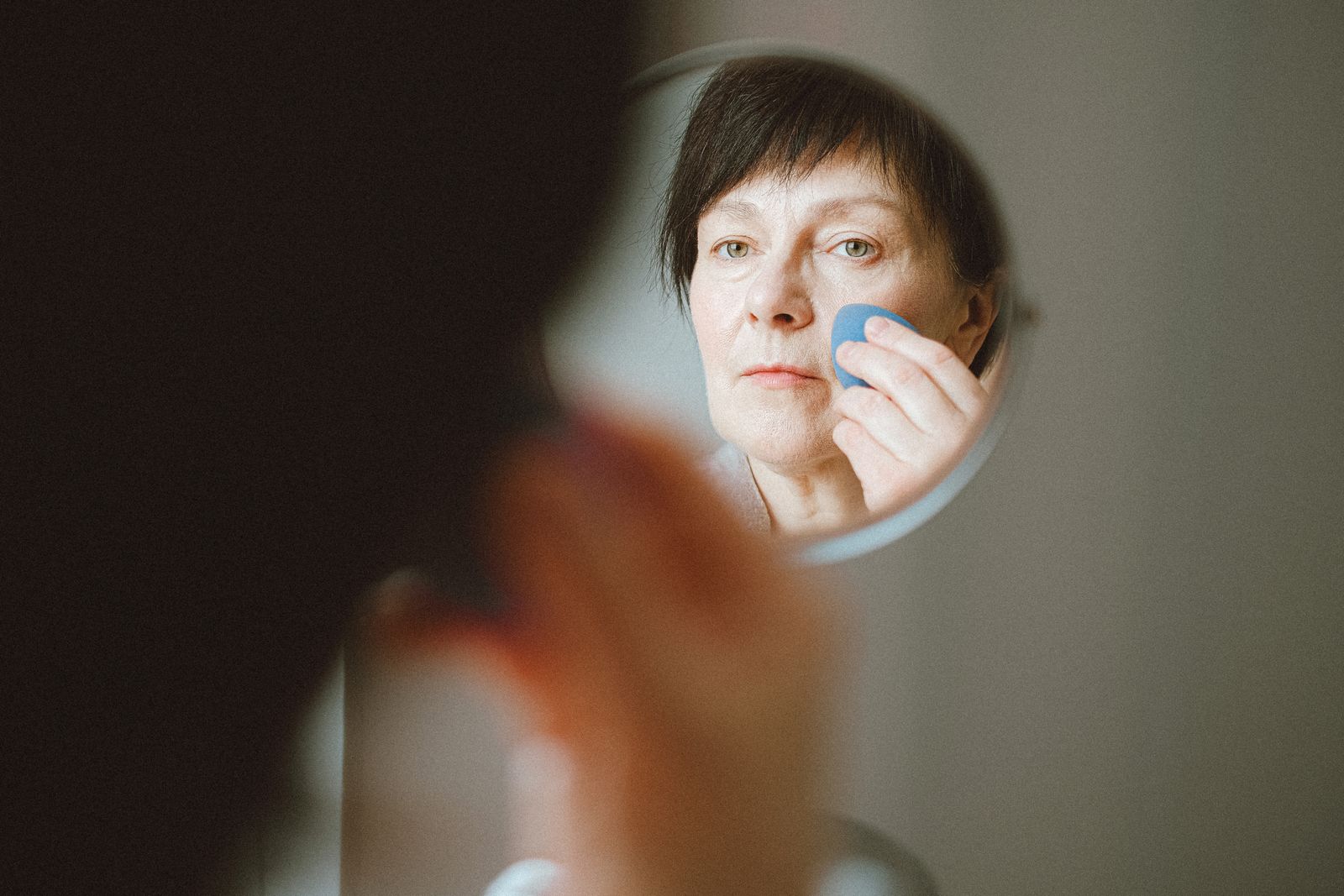 Senior woman looking closely at her face in a mirror