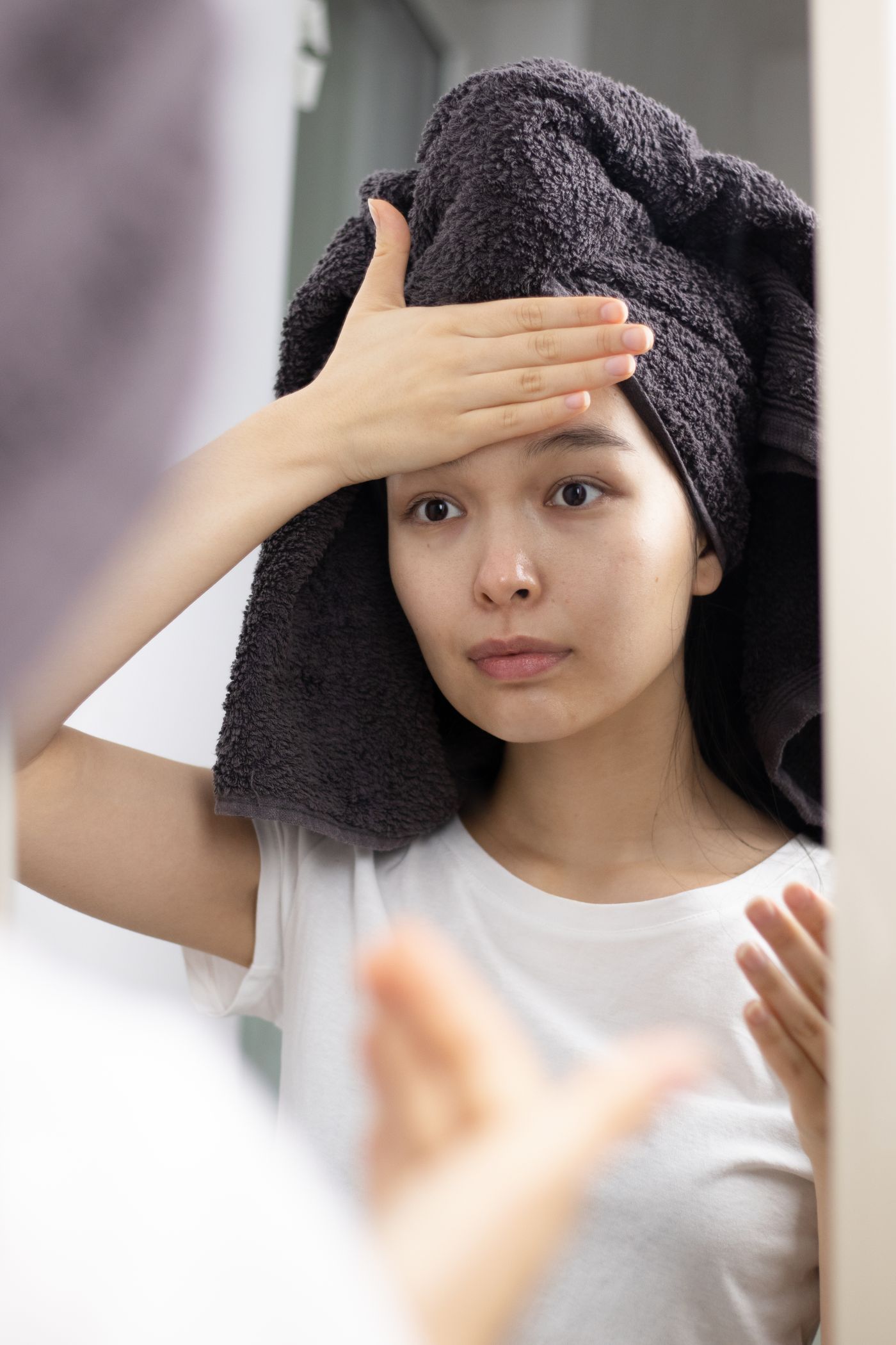Woman looking at her skin in a mirror under consistent indoor lighting