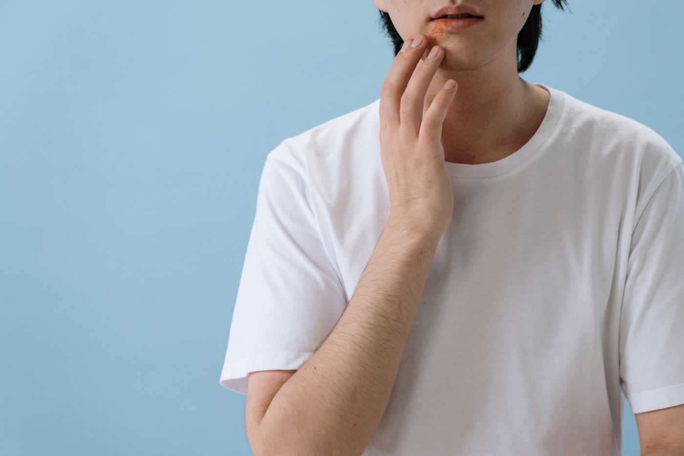 Man examining a facial skin concern with his hand