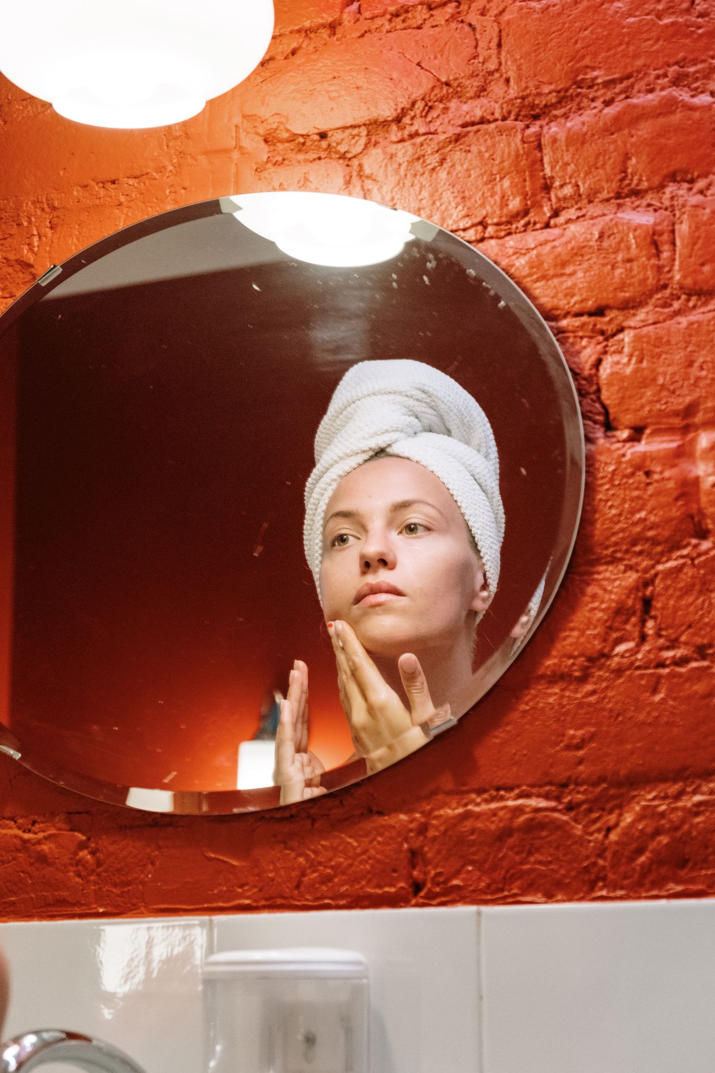 Woman applying a facial skincare product while looking in a mirror
