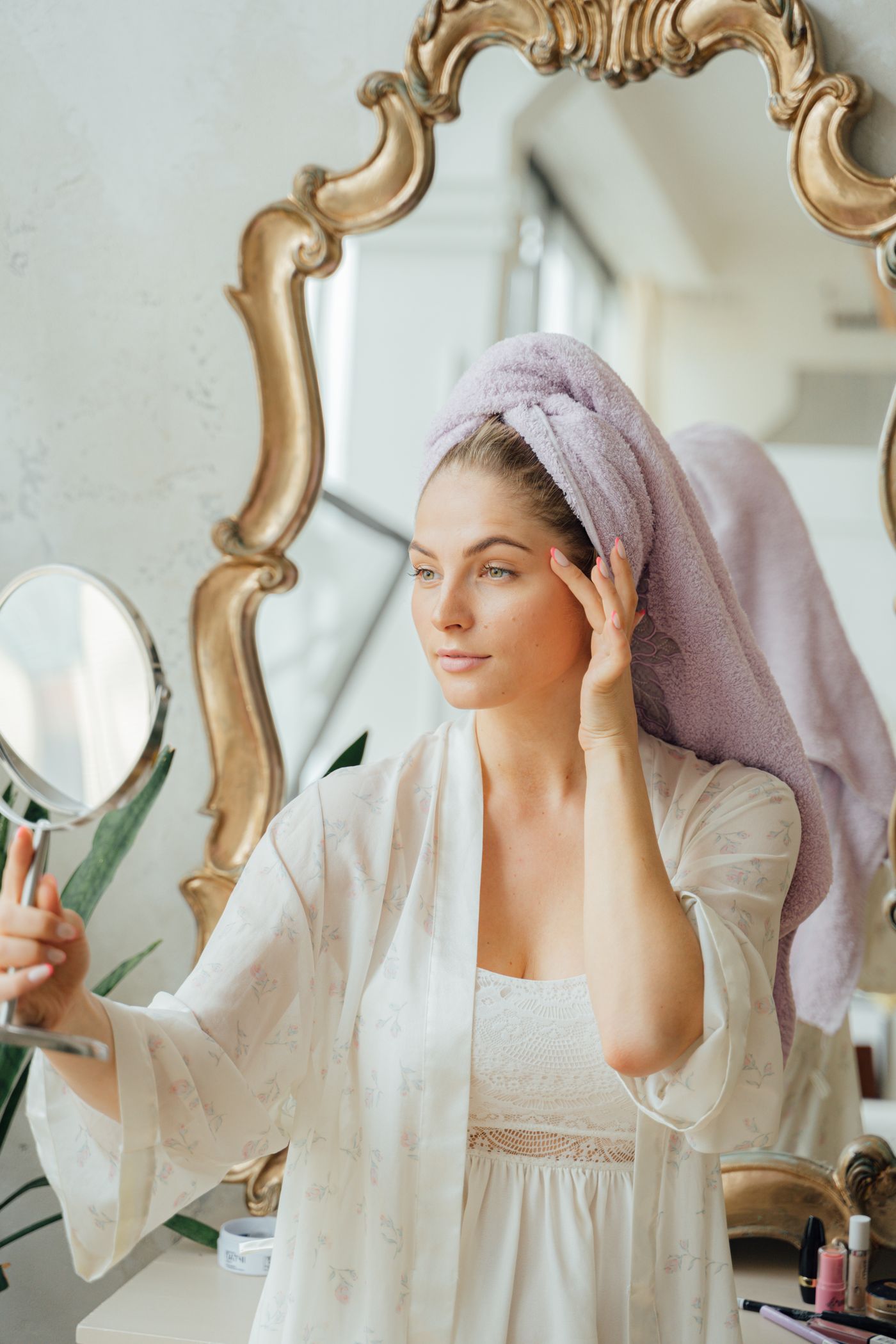 Woman examining her skin in a handheld mirror before choosing treatment