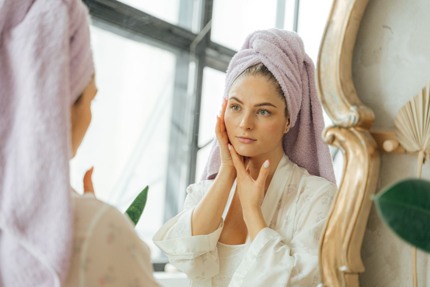 Woman observing her facial skin and contours in a mirror