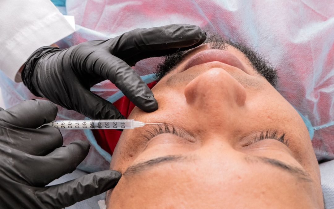 Medical practitioner performing a facial injection on a male patient